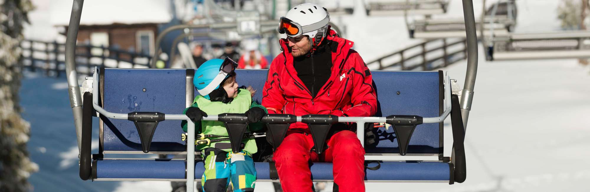 Father and son on ski lift in winter vacation resort