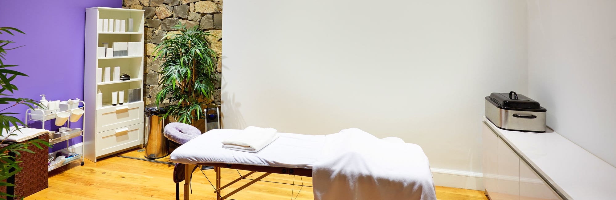 Massage room with massage table and products with stone wall