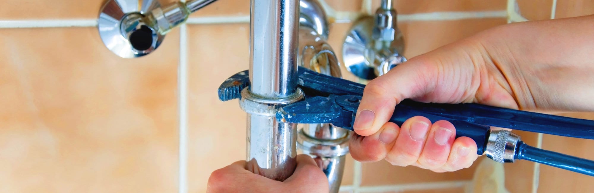 hands of a plumber with sink and wrench