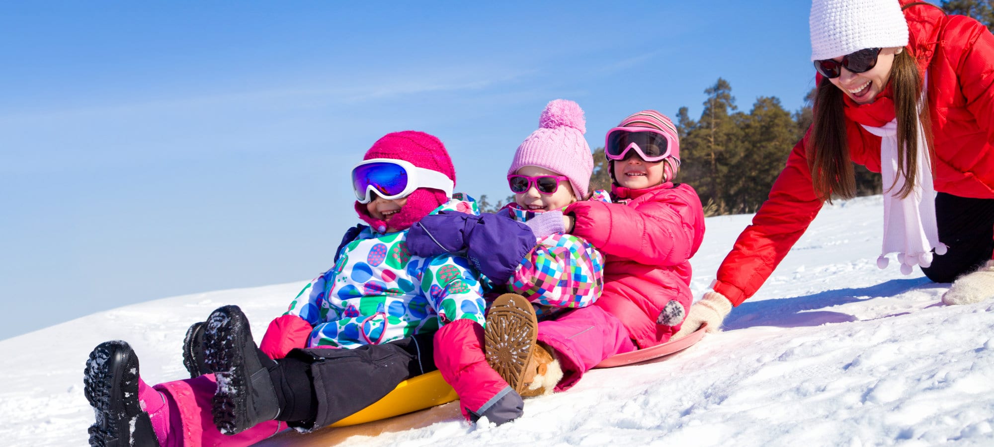 Young mother with  children riding with snow slides in winter time